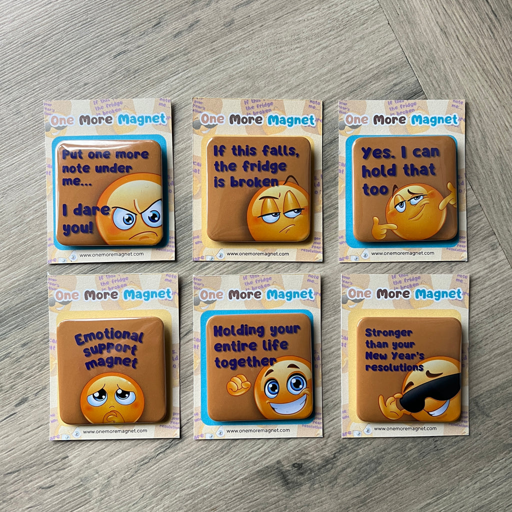Set of six emoji-themed magnets in packaging on a wooden surface