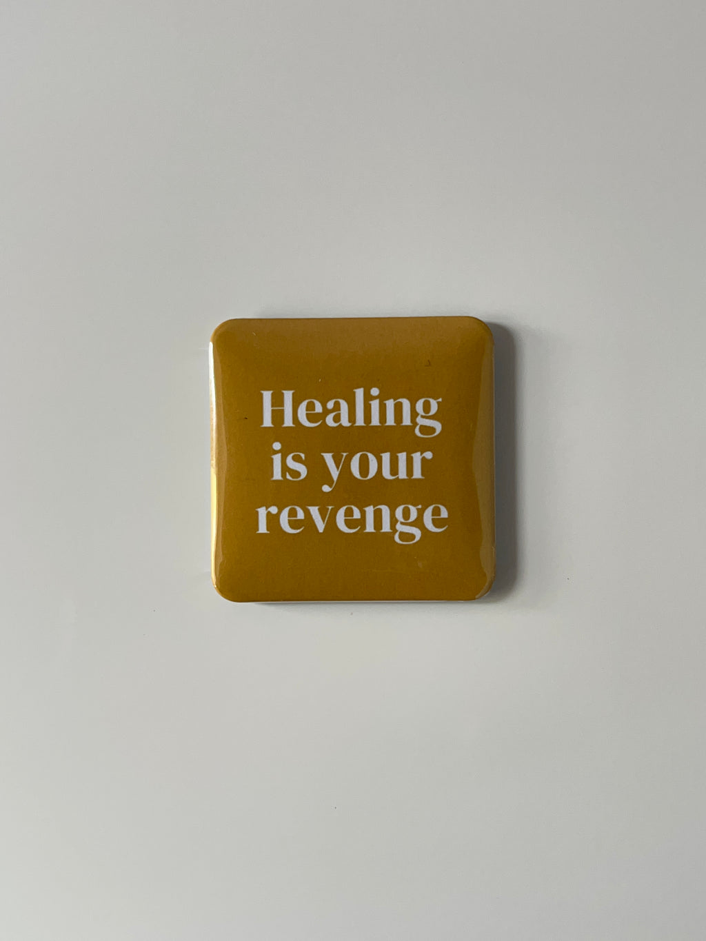 Yellow fridge magnetwith text 'Healing is your revenge' on a light gray background