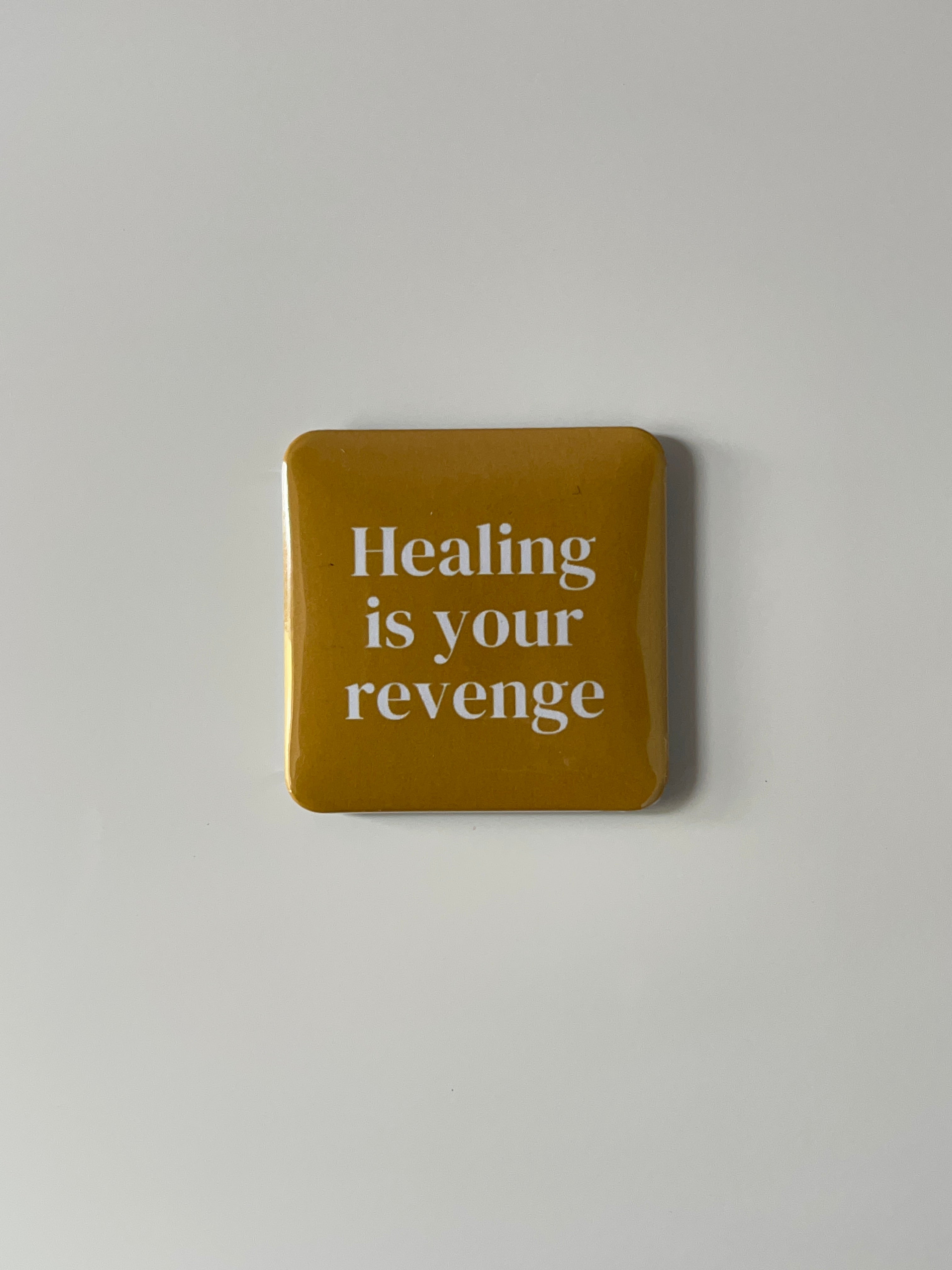 Yellow fridge magnetwith text 'Healing is your revenge' on a light gray background