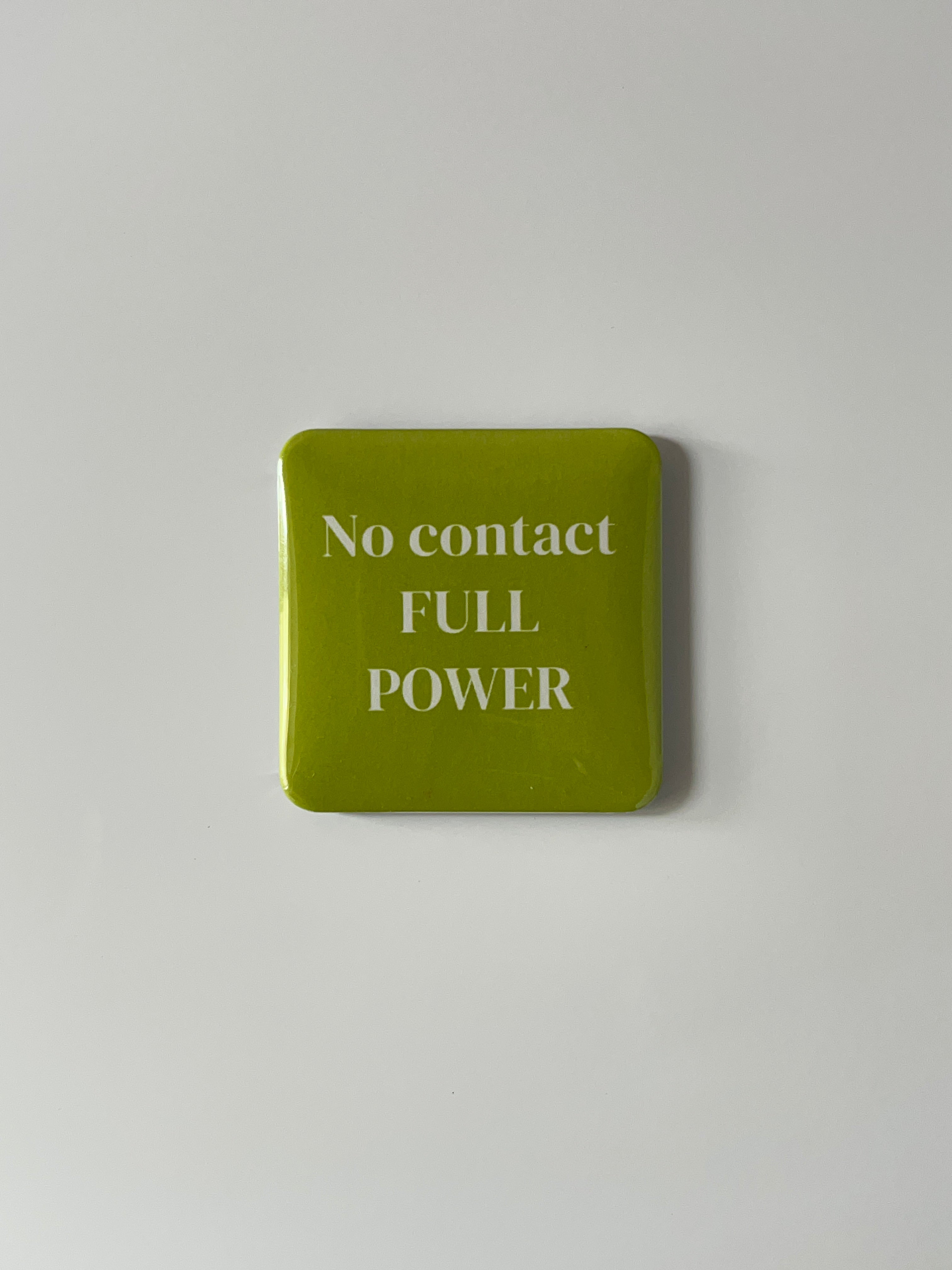Green Fridge magnet with 'No contact FULL POWER' text on a light gray background