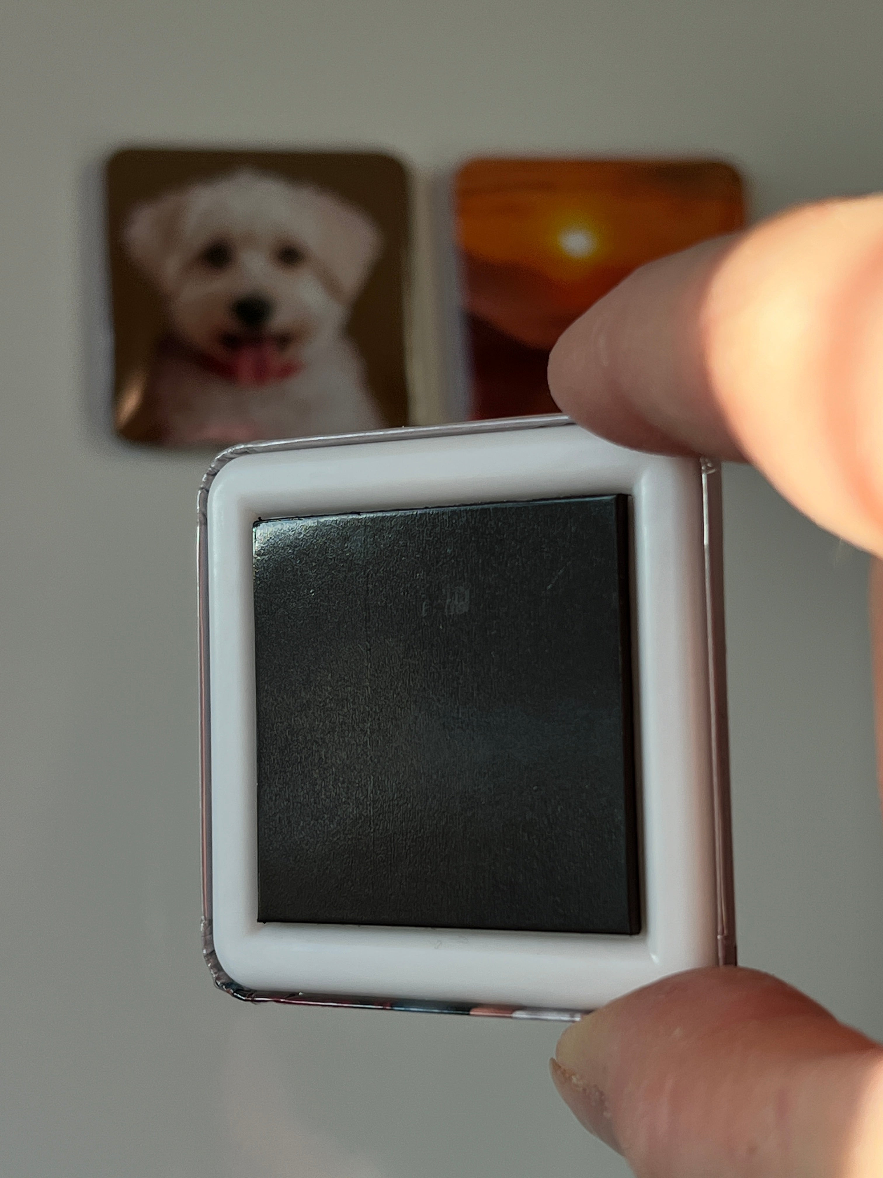 A pressed button magnet held by a hand.