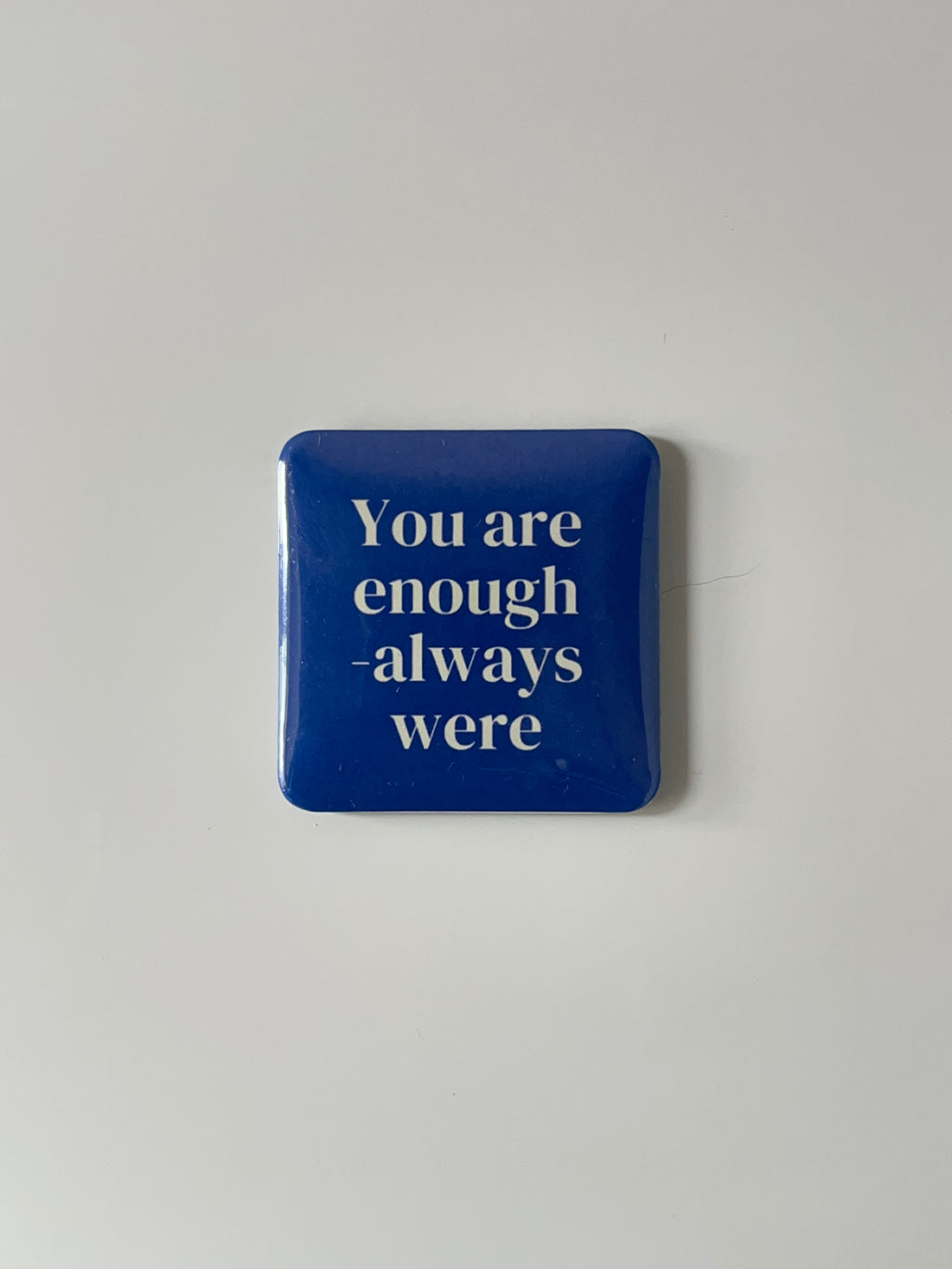 Blue fridge magnet with white text “ You are enough - always were on a light gray background