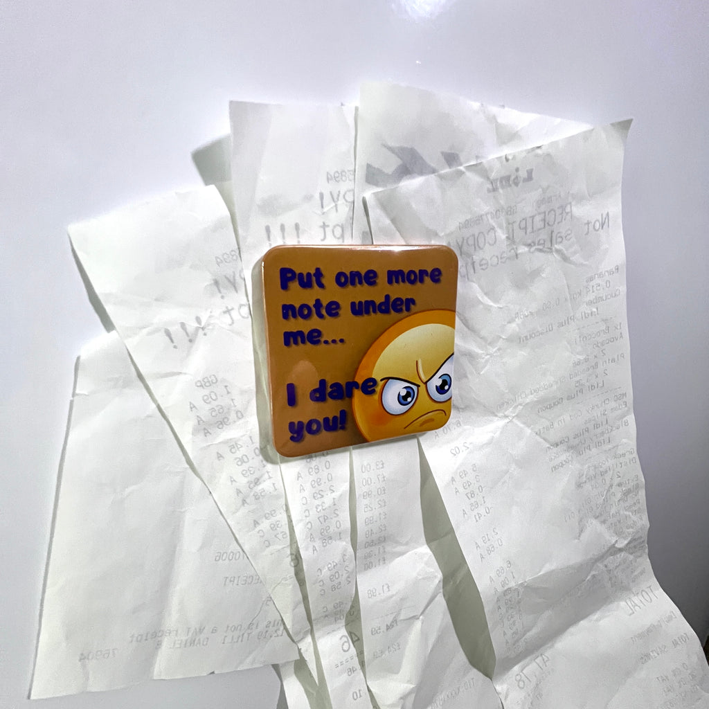 An emoji themed fridge magnet with bills underneath it on the fridge door.