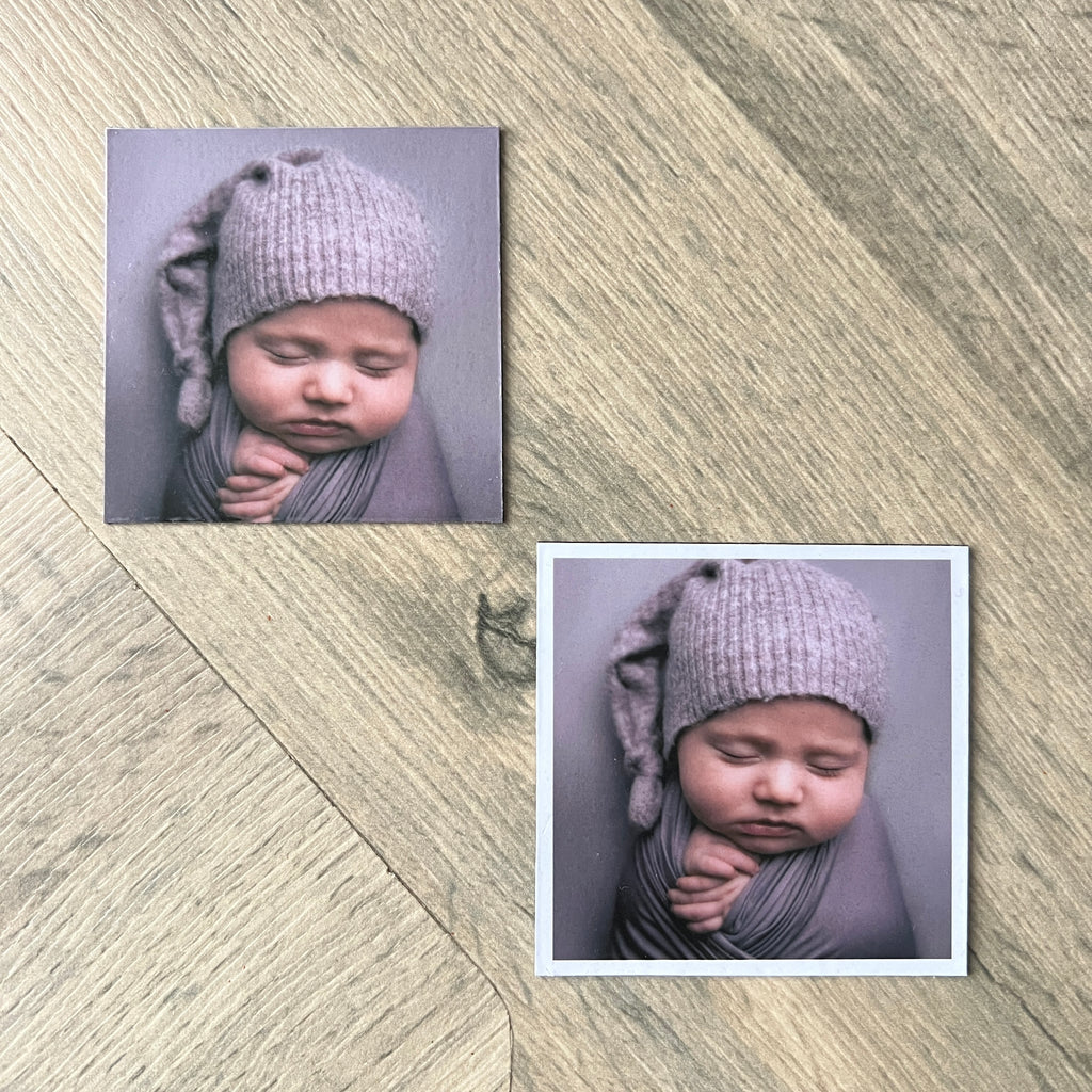 Two square fridge magnets of a baby wearing a knitted hat on a wooden surface.